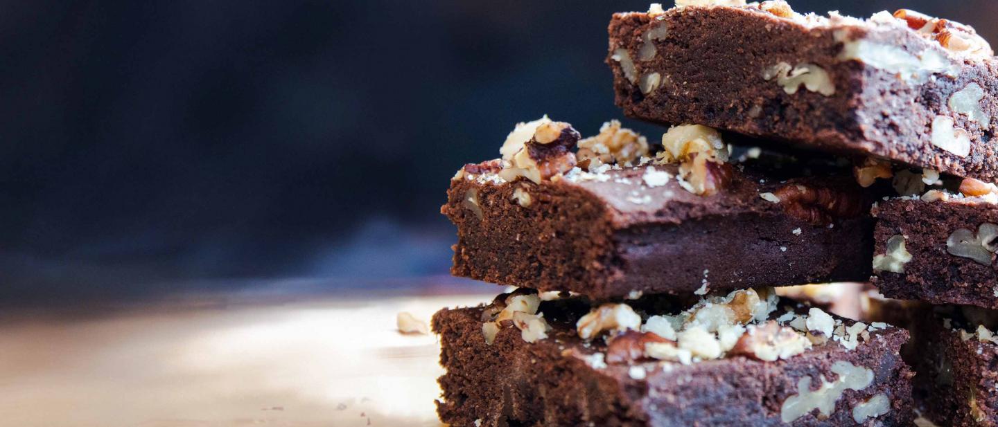 Una torre de brownies de chocolate y nueces pecanas, espolvoreadas con pedacitos de nueces pecanas y avellanas, recién salida del horno.